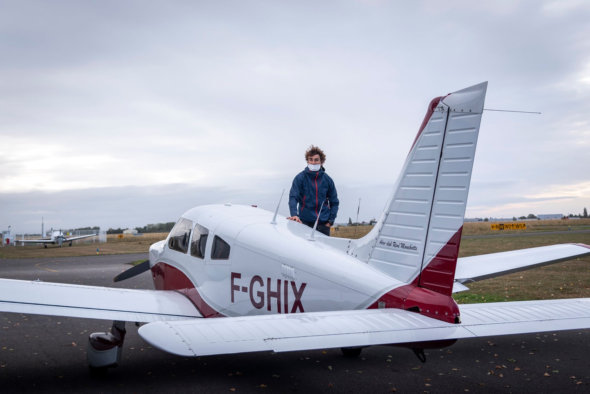 Un garçon qui pose à côté d'un avion de tourisme