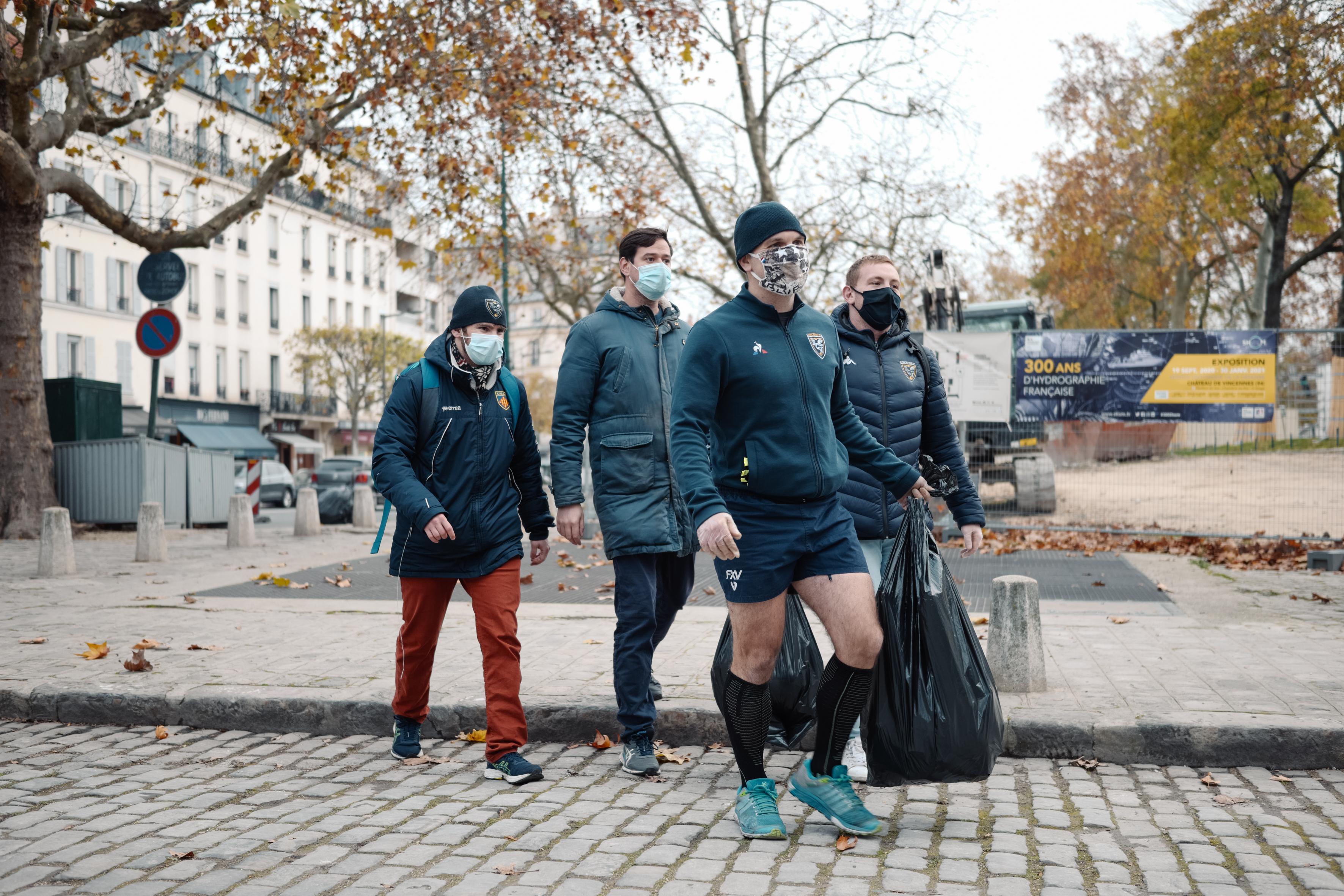 hommes qui portent des sacs de déchets dans la rue