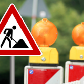 Panneau de danger signalant des travaux routiers avec un ouvrier en train de creuser.