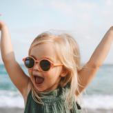 Drôle d’enfant fille jouant en plein air surpris enfant émotionnel dans des lunettes de soleil 3 ans bébé levé mains vacances en famille