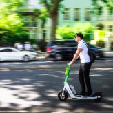 un homme circule en ville sur une trottinette électrique