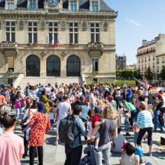 Une foule de personnes se trouve sur la place devant l'hôtel de ville de Vincennes.