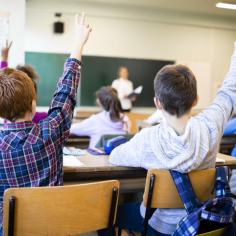 image d'enfants dans une salle de classe qui lèvent la main
