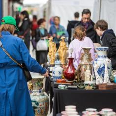 On y voit deux personnes devant un stand avec des antiquités