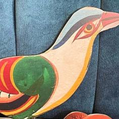 on y voit un oiseau de papier coloré posé sur un fauteuil bleu 