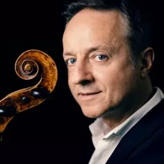 Un homme aux yeux bleu tient un violon