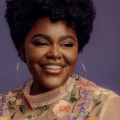 une femme souriante porte de grandes créoles 