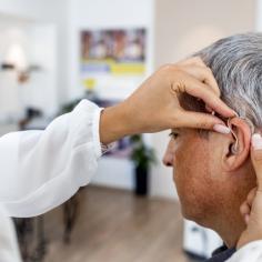 Femme médecin équipe un patient masculin d’une aide auditive