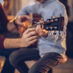Garçon dans l'école de guitare avec l'enseignant apprenant à jouer