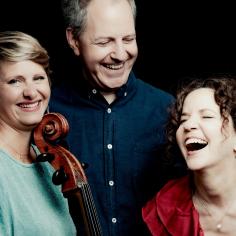 Un groupe de 3 artistes rient ensemble