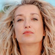 Une femme blonde en pleine nature regarde l'objectif