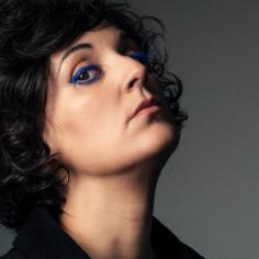 Une femme brune regarde la caméra et porte un eye liner bleu électrique