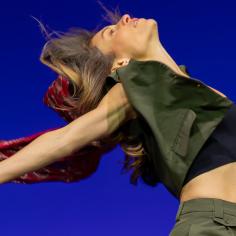 une femme danse sur une scène à fond bleu électrique