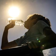 une personne qui boit de l'eau sous un soleil