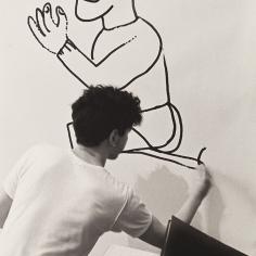 un jeune homme dessine sur un mur
