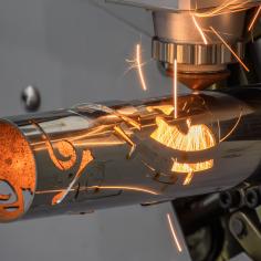 Scène rapprochée de la machine de découpe laser à fibre a coupé le tube en acier inoxydable et la lumière étincelante.