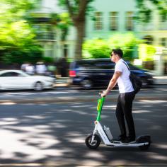 un homme circule en ville sur une trottinette électrique