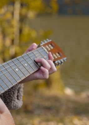 Gros plan des mains de l’artiste joue de la guitare acoustique en bois dans le parc d’automne. 