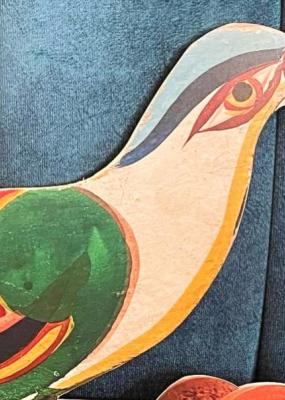 on y voit un oiseau de papier coloré posé sur un fauteuil bleu 