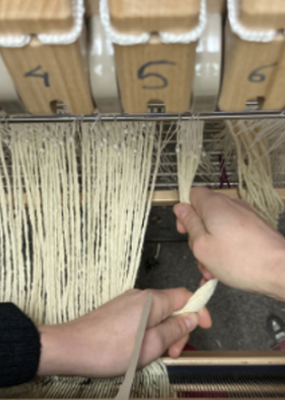 des personnes tiennent de la laine sur une machine à tisser