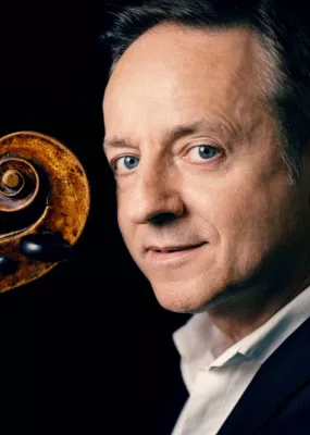 Un homme aux yeux bleu tient un violon