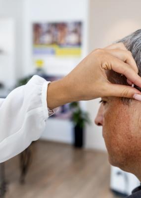 Femme médecin équipe un patient masculin d’une aide auditive