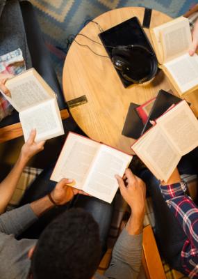 Groupe diversifié d’amis discutant d’un livre en bibliothèque.