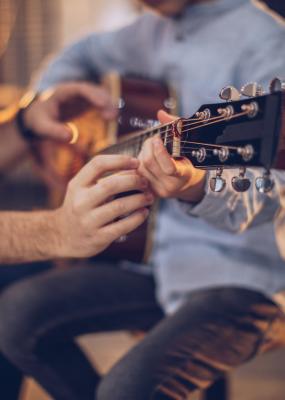 Garçon dans l'école de guitare avec l'enseignant apprenant à jouer