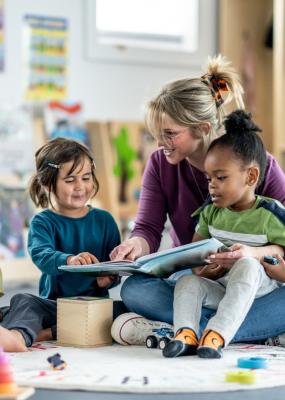 Enseignant lisant un livre à de jeunes enfants dans une salle de jeux