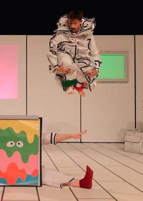 Deux danseurs déguisés sur scène, l'un saute et l'autre est assis