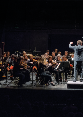Un collage de deux photos, d'une part un homme d'un certaine âge, de l'autre un orchestre d'artistes à vent 