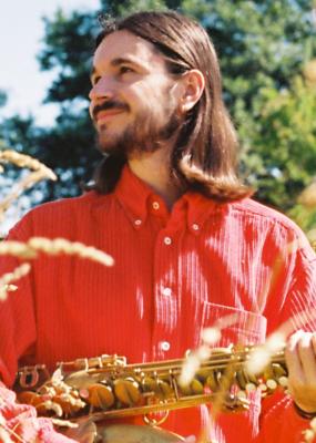 Un homme au cheveu long tient un saxophone dans la ses mains