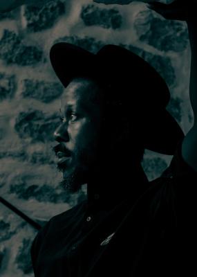 Un homme est photographié de profil et il porte un chapeau