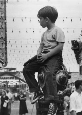 Photo d'un petit garçon en noir et blanc perché sur une bouche d'eau