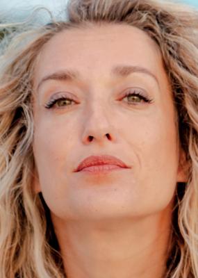 Une femme blonde en pleine nature regarde l'objectif