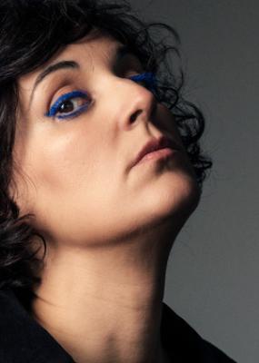 Une femme brune regarde la caméra et porte un eye liner bleu électrique