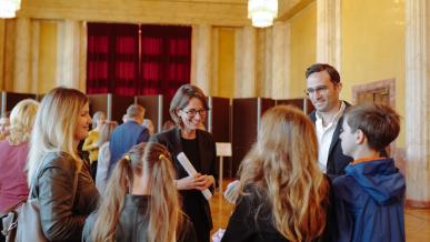Des personnes, dont des enfants, discutent avec des adultes dans un hall d'hôtel de ville.