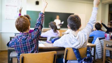 image d'enfants dans une salle de classe qui lèvent la main