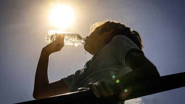 une personne qui boit de l'eau sous un soleil
