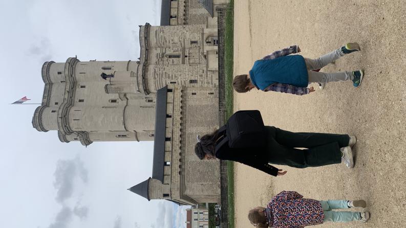 Photo d'un adulte et deux enfants devant le donjon du Château