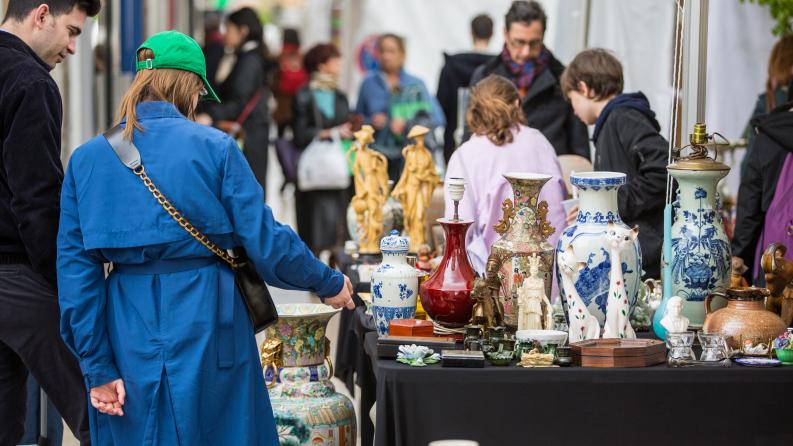 On y voit deux personnes devant un stand avec des antiquités
