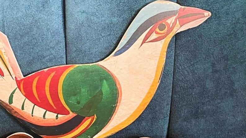 on y voit un oiseau de papier coloré posé sur un fauteuil bleu 