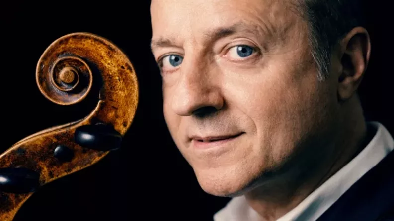 Un homme aux yeux bleu tient un violon