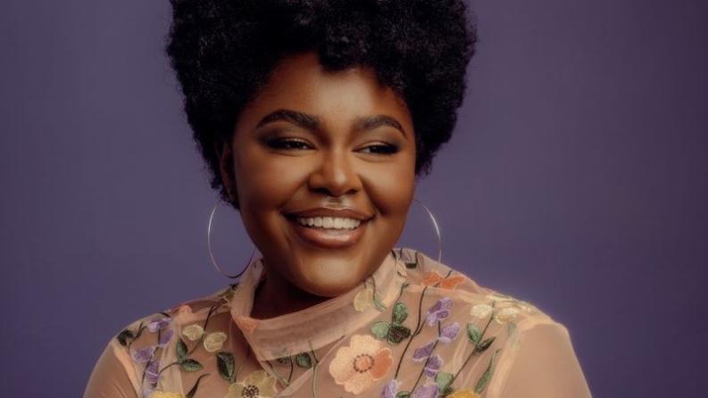 une femme souriante porte de grandes créoles 