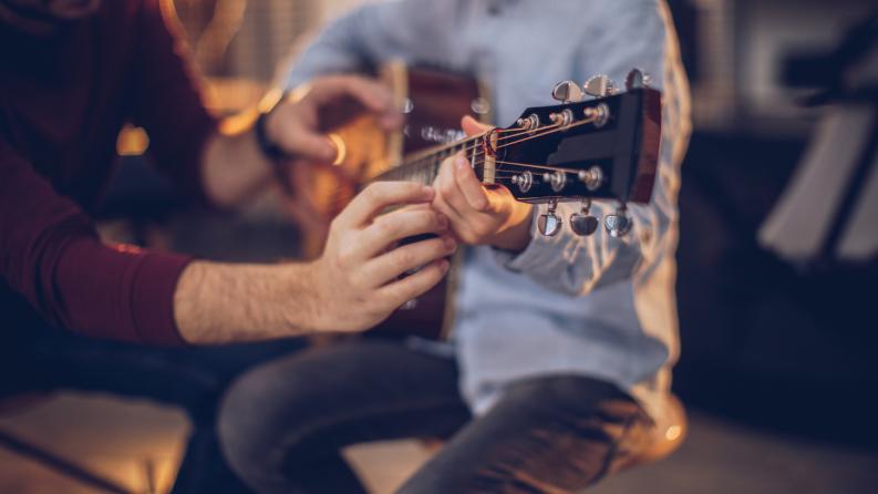 Garçon dans l'école de guitare avec l'enseignant apprenant à jouer
