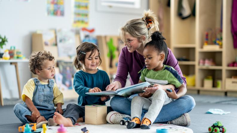 Enseignant lisant un livre à de jeunes enfants dans une salle de jeux