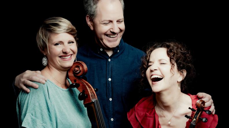 Un groupe de 3 artistes rient ensemble