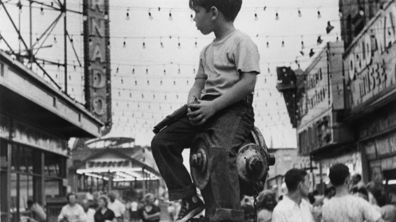 Photo d'un petit garçon en noir et blanc perché sur une bouche d'eau