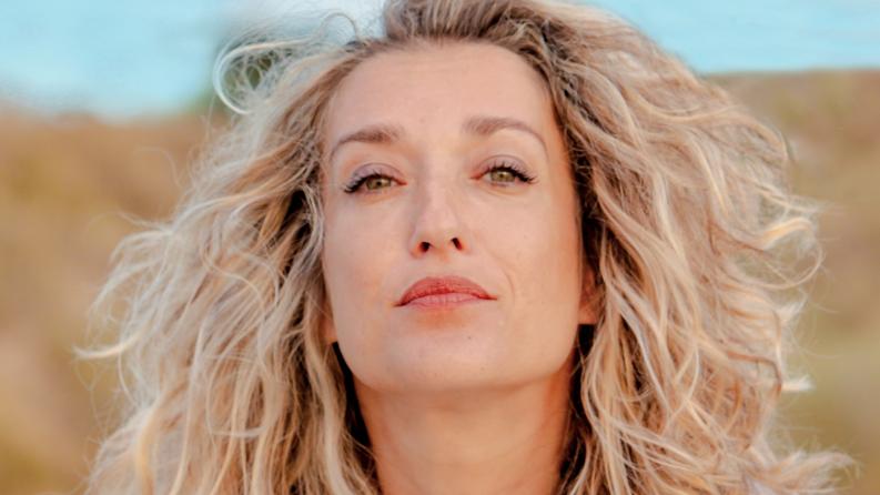 Une femme blonde en pleine nature regarde l'objectif