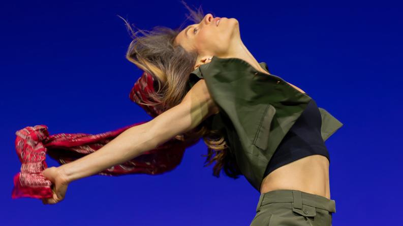 une femme danse sur une scène à fond bleu électrique